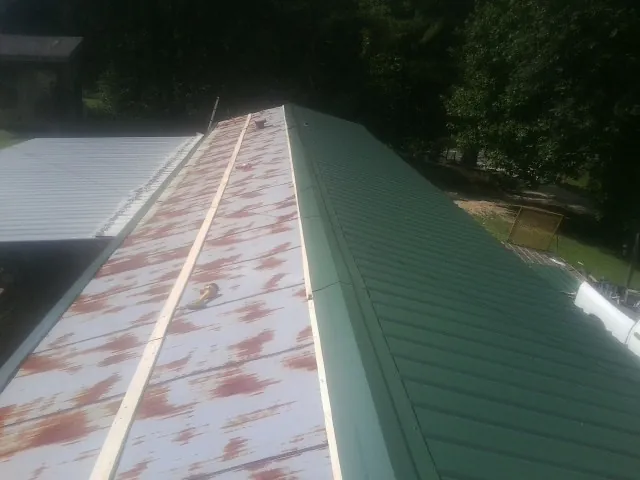 Old rusted panels beside newly installed green metal roofing — Wind Damage Roof Repair by Roofing Brothers in Wesley