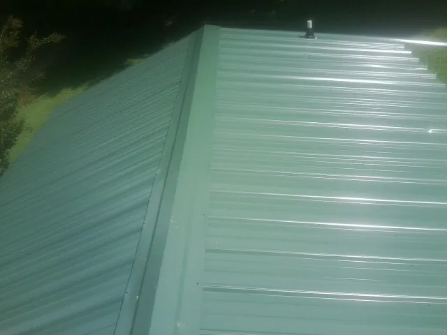 New green metal panels meeting at the ridge of a roof — Flat Roof Repair work by our crew in Wesley