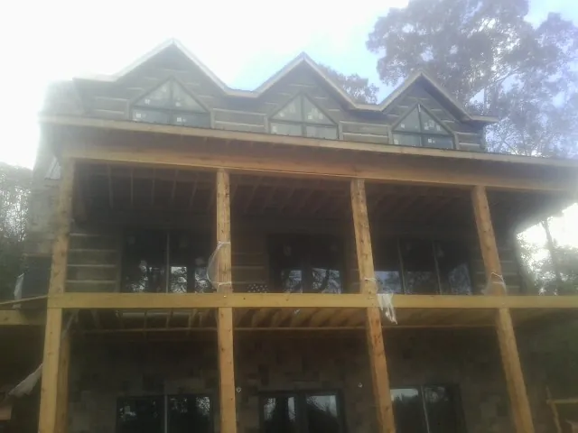 Dormers and porch framing on a large log home under construction — Roof Coating work by our crew in Wesley