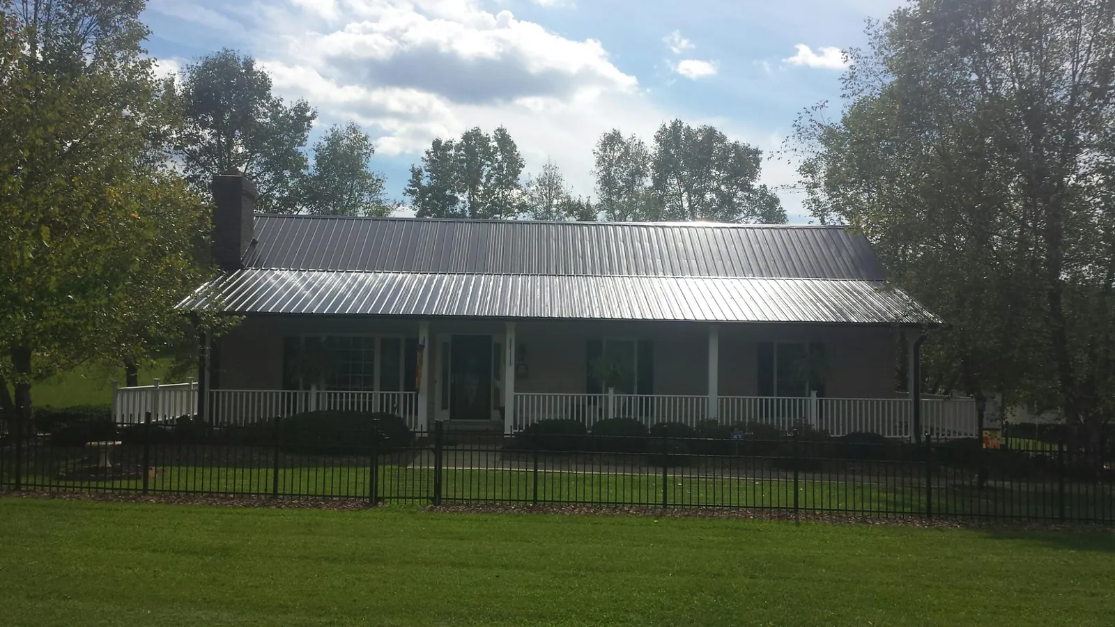 Gray metal roof on a brick ranch with a full width front porch — Gutter Guard Installation work by our crew in Wesley