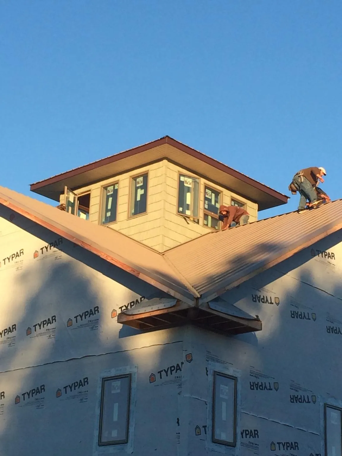 Roofers working around a rooftop cupola on a new metal roof at sunset — Roof Waterproofing in Wesley by Roofing Brothers